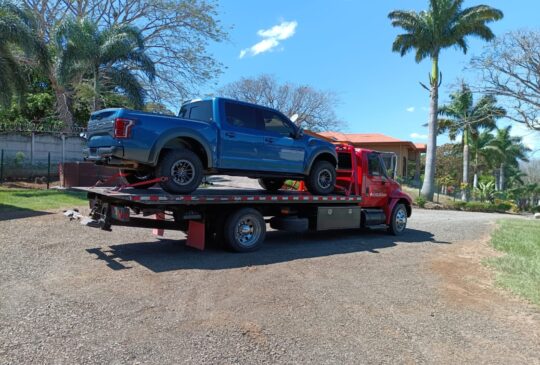 Pickup azul cargado sobre la plataforma de la grúa en Alajuela