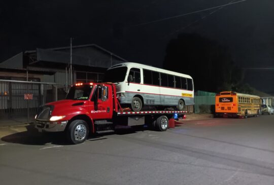 Servicio de grúa nocturno trasladando un microbús