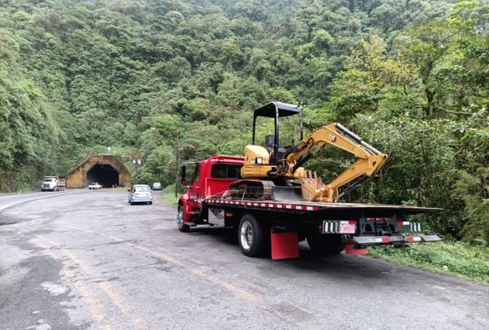 Plataforma transportando una excavadora compacta por carretera